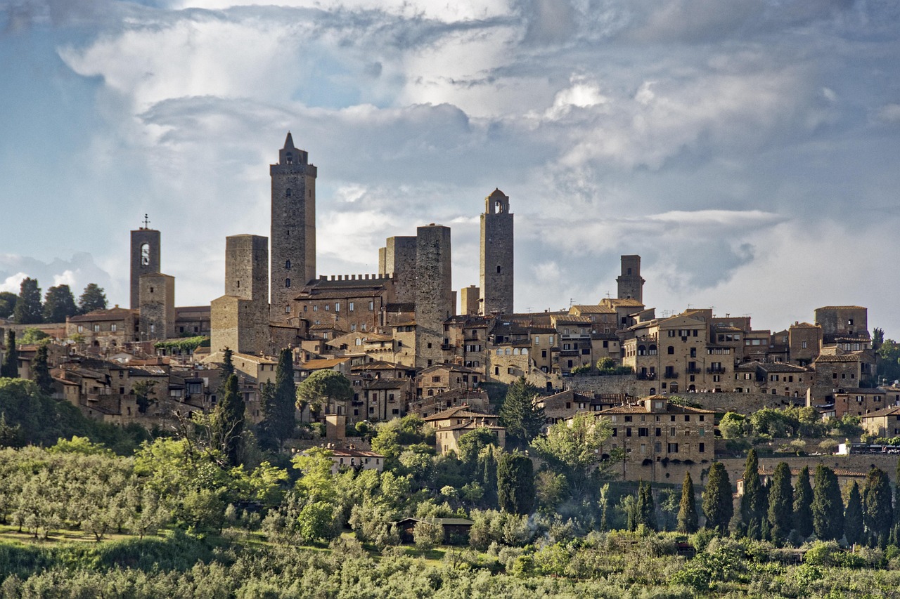 Vista panoramica di San Gimignano innevato, con torri medievali e paesaggio toscano invernale.