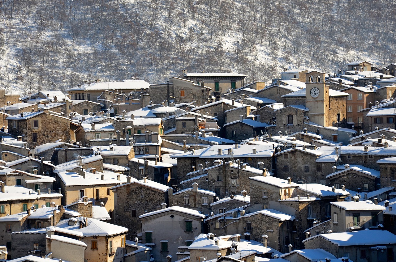 Panorama di Aosta vecchia con edifici medievali coperti di neve in un'atmosfera invernale suggestiva.