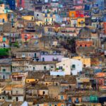 Borgo italiano colorato con case vivaci e fiori, che sembra un dipinto.