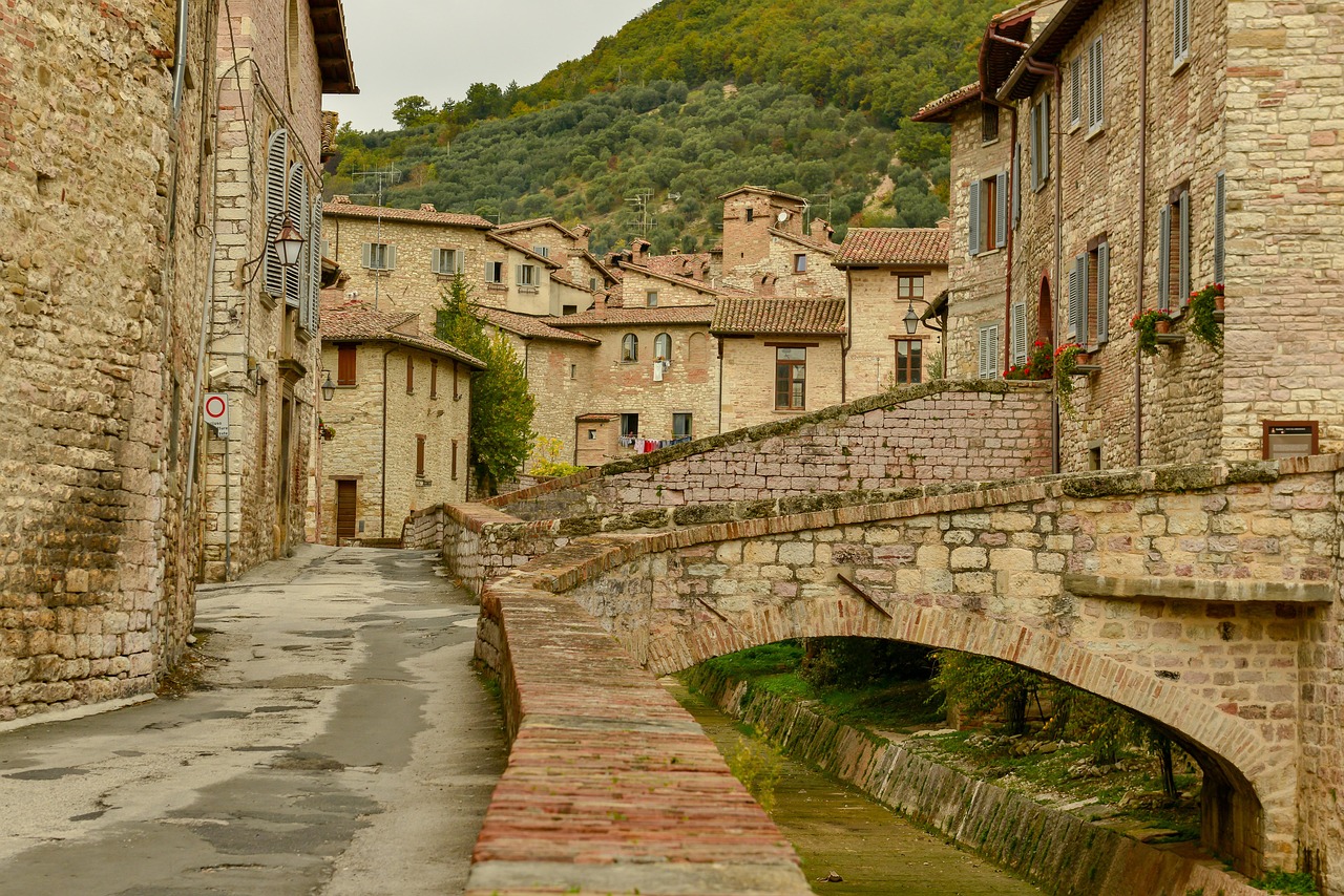 Panorama di un paese toscano con case colorate e colline verdi, simile a un dipinto.