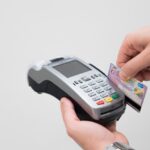 Carta contactless in mano, evidenziando il rischio di furto di dati e truffe.