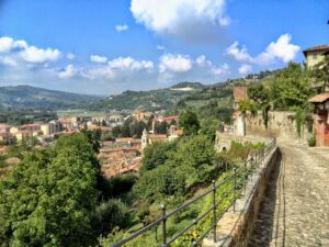 Panorama del paese piemontese, con colline verdi e architettura caratteristica, immerso nella luce del sole.