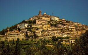 Vista panoramica di un pittoresco paese marchigiano con antiche architetture e colline verdi.