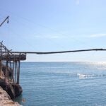 Pescatori a Porto Badisco gustano ricci di mare con pane sugli scogli.