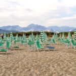 Spiaggia italiana premiata con acque cristalline e sabbia fine, vista panoramica di bagnanti e ombrelloni.