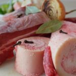 Brodo di carne fatto in casa in una pentola, con ingredienti freschi e aromatici visibili.